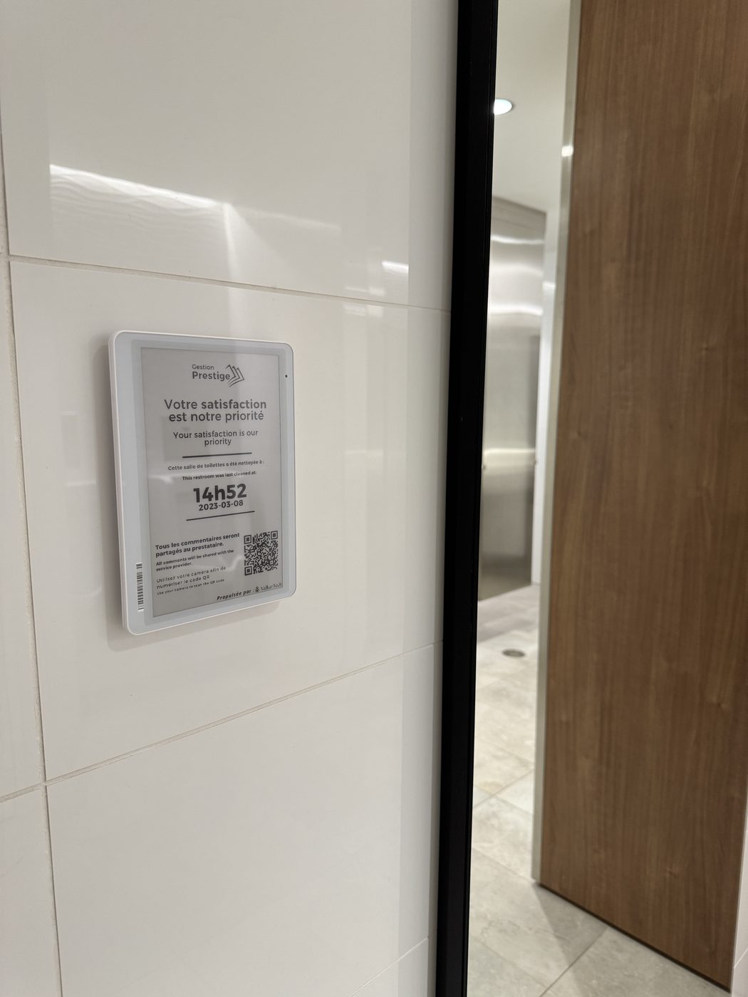 Photo : écran Service+ installé sur le mur au-dessus d'un comptoir de salle de bain, à hauteur d'usage.
